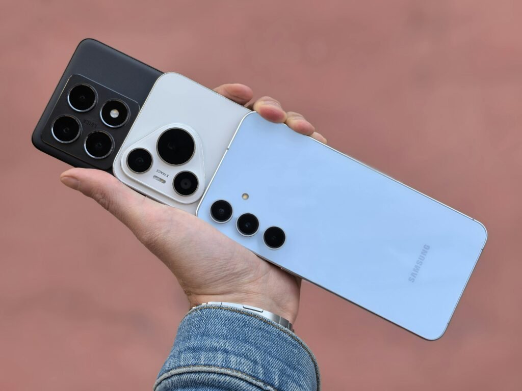 A hand holding three smartphones showcasing various camera designs.