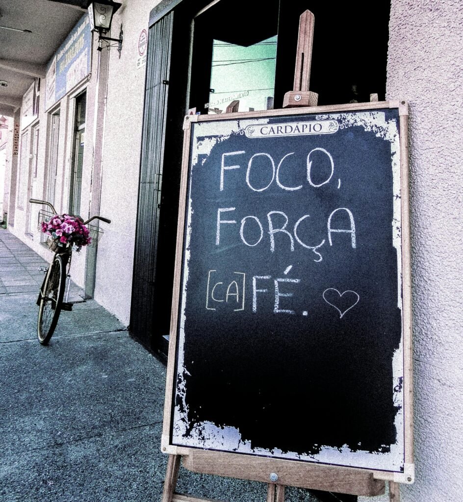 A vintage chalkboard sign outside a café with inspiring text next to a bicycle with flowers.