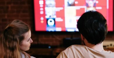 A couple sitting together in a cozy living room, watching a movie on a smart TV.
