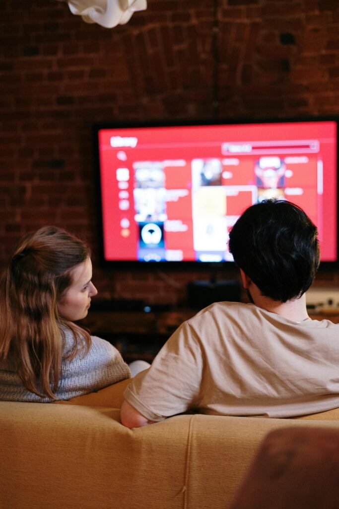 A couple sitting together in a cozy living room, watching a movie on a smart TV.