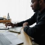 Pessoa sentada à noite usando o celular e refletindo sobre hábitos que impactam o controle do dinheiro e os gastos do dia a dia.