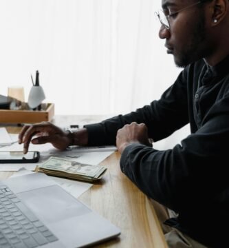 Pessoa sentada à noite usando o celular e refletindo sobre hábitos que impactam o controle do dinheiro e os gastos do dia a dia.