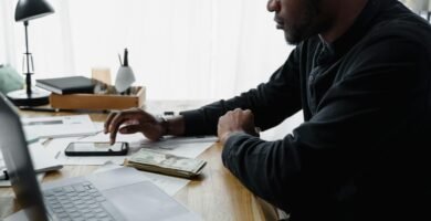 Pessoa sentada à noite usando o celular e refletindo sobre hábitos que impactam o controle do dinheiro e os gastos do dia a dia.