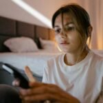 Pessoa usando celular com expressão de cansaço mental