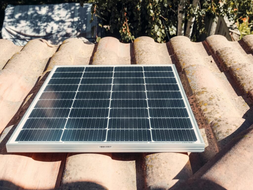 A single solar panel on a rustic tiled roof gleaming in sunlight. Eco-friendly energy.